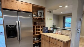 A modern kitchen with wooden cabinets, a stainless steel refrigerator, a built-in oven, and a window providing natural light. - Spacious and comfortable 5 bed, hot tub, home theater, fireplaces (Boulder)