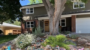 A two-story house with a front yard featuring a rock garden and various decorative items. - Spacious and comfortable 5 bed, hot tub, home theater, fireplaces (Boulder)