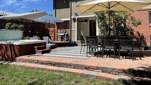 A patio area with a grill, outdoor seating, and a covered table under a large umbrella. - Spacious and comfortable 5 bed, hot tub, home theater, fireplaces (Boulder)