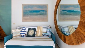 Un dormitorio con una cama, almohadas a rayas, un cojín decorativo y un espejo grande.