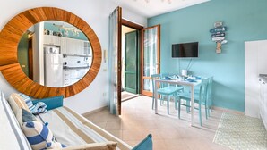 Una cocina moderna con armarios blancos, un espejo grande y una zona de comedor con sillas azules y una mesa.