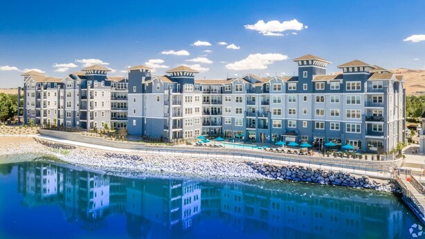 A multi-story hotel with a pool area and a view of the water. - Sparks Marina 2BR · Mountain Views, Pool & Gym (Sparks)