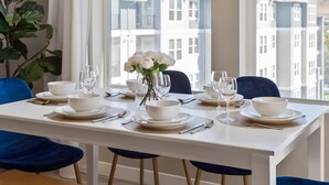A dining table set for four with white tableware and a vase of white flowers. - Sparks Marina 2BR · Mountain Views, Pool & Gym (Sparks)