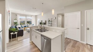 A modern kitchen with a dishwasher, a dining area with a table and chairs, and a view of the outdoors. - Sparks Marina 2BR · Mountain Views, Pool & Gym (Sparks)