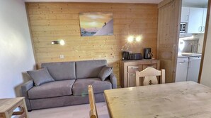 Uma sala de estar acolhedora com um sofá cinzento, mesa de jantar de madeira e um quadro na parede.