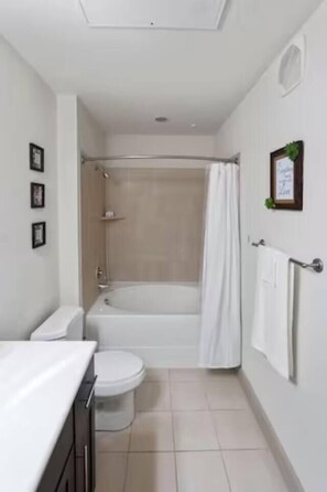 Une salle de bain avec une baignoire, des toilettes et un rideau de douche.