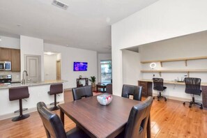 A modern kitchen with a microwave, sink, and a dining area with a wooden table and chairs.