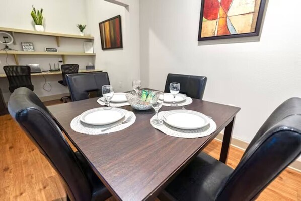 A dining table set for four with a decorative centerpiece, surrounded by black chairs.