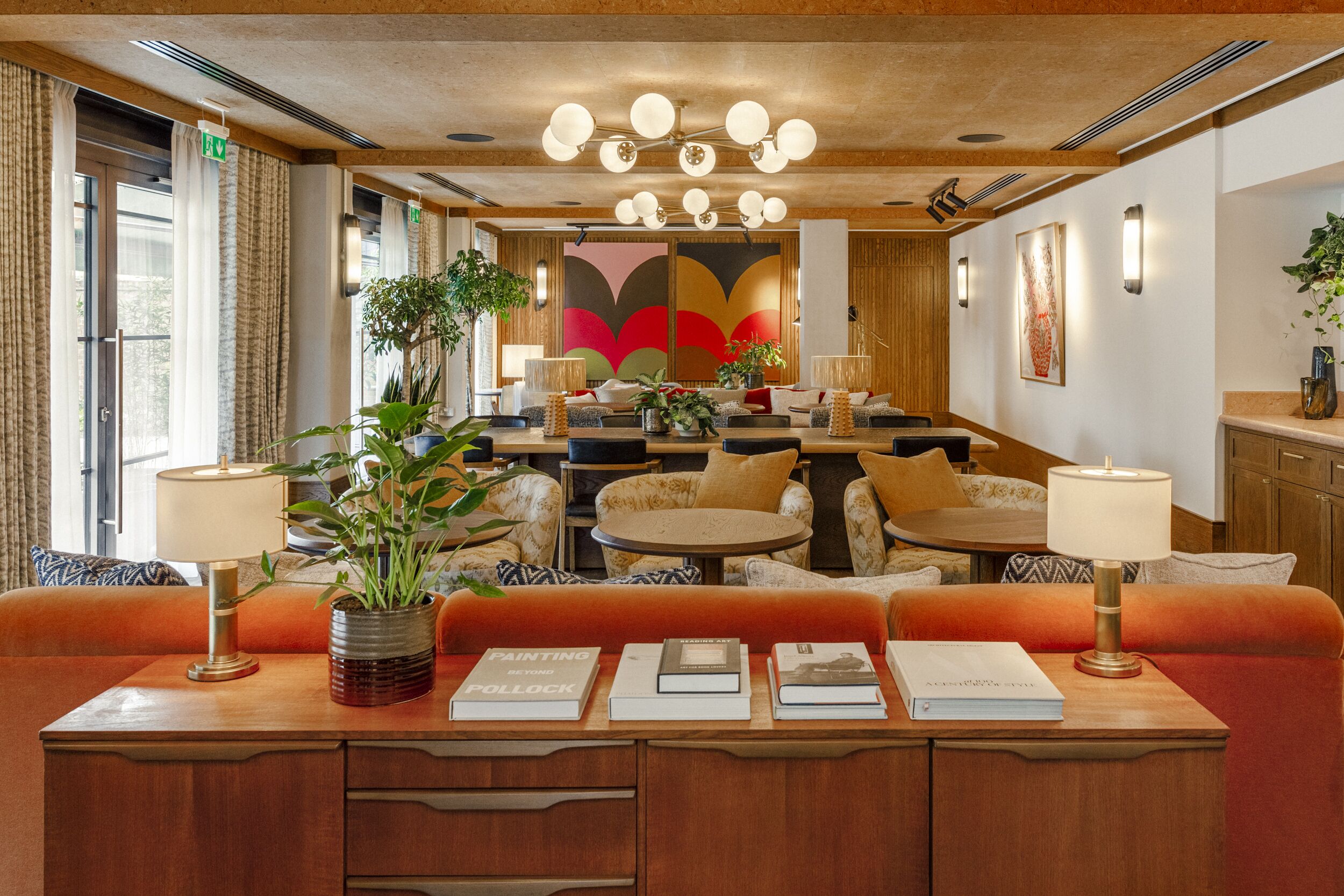 Een hotellobby met een centraal zitgedeelte, een receptiebalie en een groot abstract schilderij aan de muur.