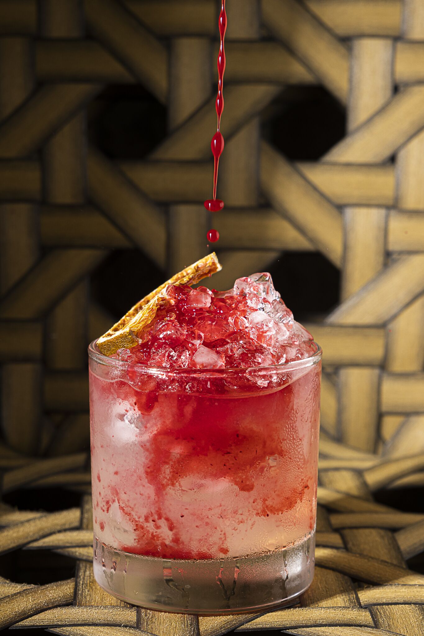 Een cocktail met ijs en garnering in een glas.