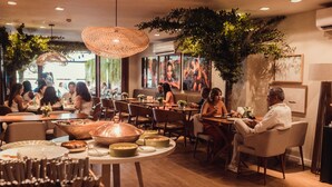 Ein Restaurant mit runden Tischen, Stühlen und einem großen Tisch in der Mitte mit einem Kupfertopf.