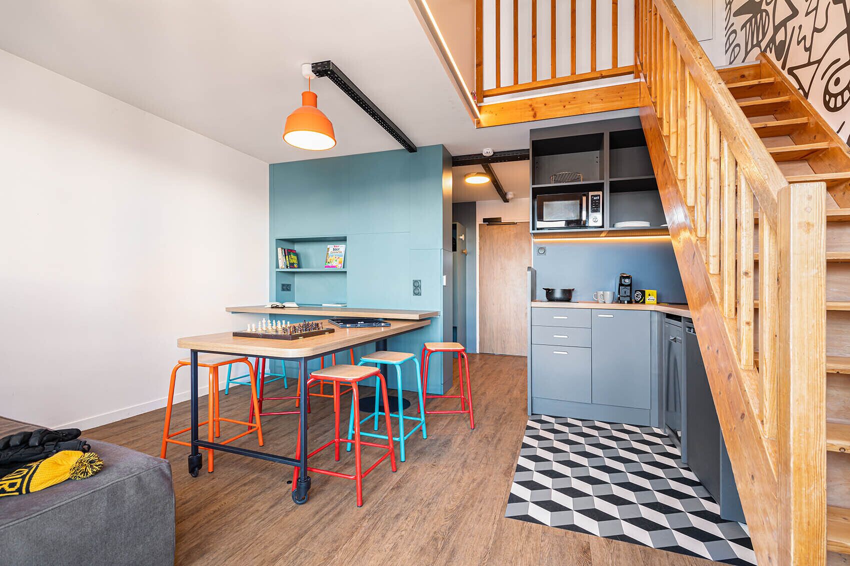 Cozinha compacta com mesa de madeira, banquetas e micro-ondas.