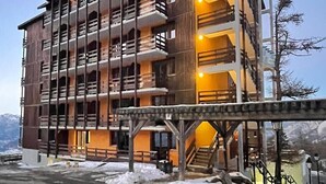 Un hotel de diverses plantes amb balcons, una escala i vista a les muntanyes.