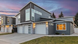 Une maison moderne à deux étages, dotée d’un garage, de détails en pierre et d’une pelouse bien entretenue.