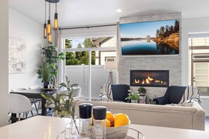 Una sala de estar moderna con chimenea, un comedor y un televisor grande montado en la pared.