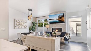Un salon moderne avec une cheminée, un coin repas et une grande fenêtre.