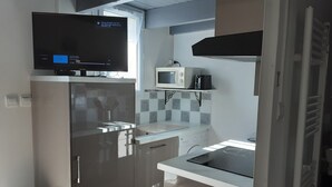 A compact kitchen with a built-in microwave, a stainless steel refrigerator, and a sink.