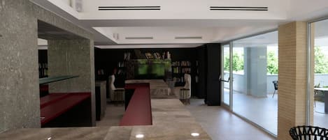 A modern interior with a stone reception desk, a red bench, and a bookshelf.
