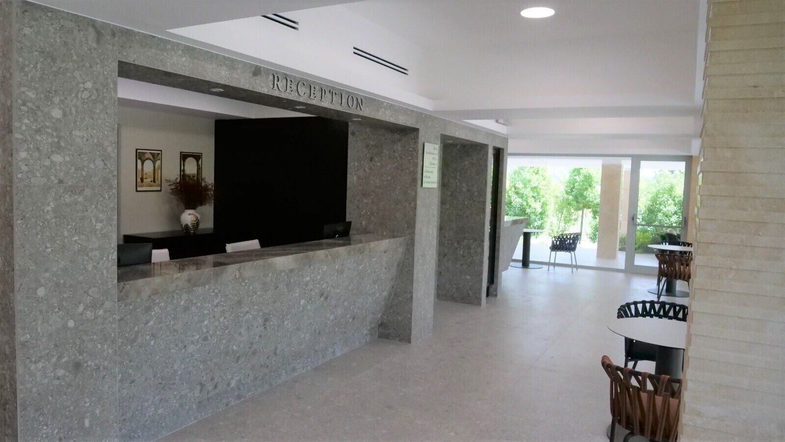 A reception area with a marble counter, framed artwork, and a sign indicating a waiting area.