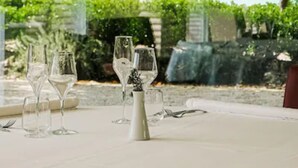 A table set for dining with clear glassware and a vase, overlooking a well-manicured garden and a pool. - Kairos Resort (Piedimonte San Germano)