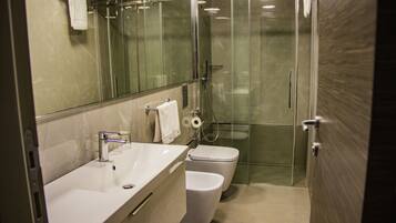 Un baño moderno con ducha envuelta en vidrio, un lavabo blanco y un inodoro.