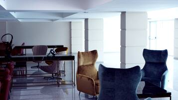 Ein geräumiger Raum mit modernem Design, der eine Essecke mit Tisch und Stühlen sowie eine Sitzecke mit zwei Sesseln und einer Couch bietet.