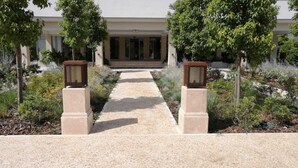 A pathway leading to a building with a modern design, flanked by trees and decorative planters. - Kairos Resort (Piedimonte San Germano)