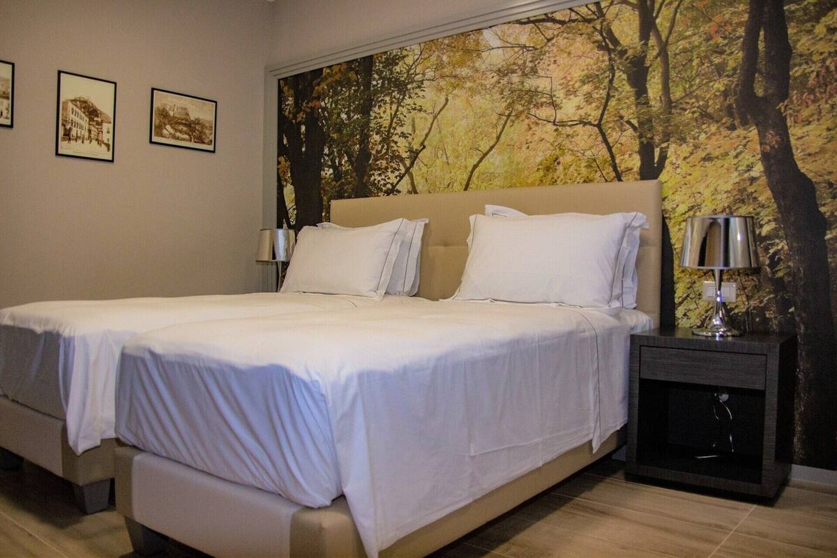 A bedroom with a large bed, a nightstand, and a wall mural.