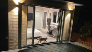 A sliding glass door leading to a bedroom with a bed and a desk. - Contemporary Guest House With Outside Barrel Sauna (Wadebridge)