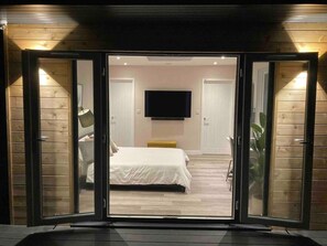 A bedroom with a bed, a television, and a sliding door leading to another room. - Contemporary Guest House With Outside Barrel Sauna (Wadebridge)