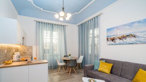 Ein modernes Wohnzimmer mit Essbereich, ein graues Sofa mit gelben Kissen, ein weißer Couchtisch und ein Gemälde eines Leuchtturms an der Wand.