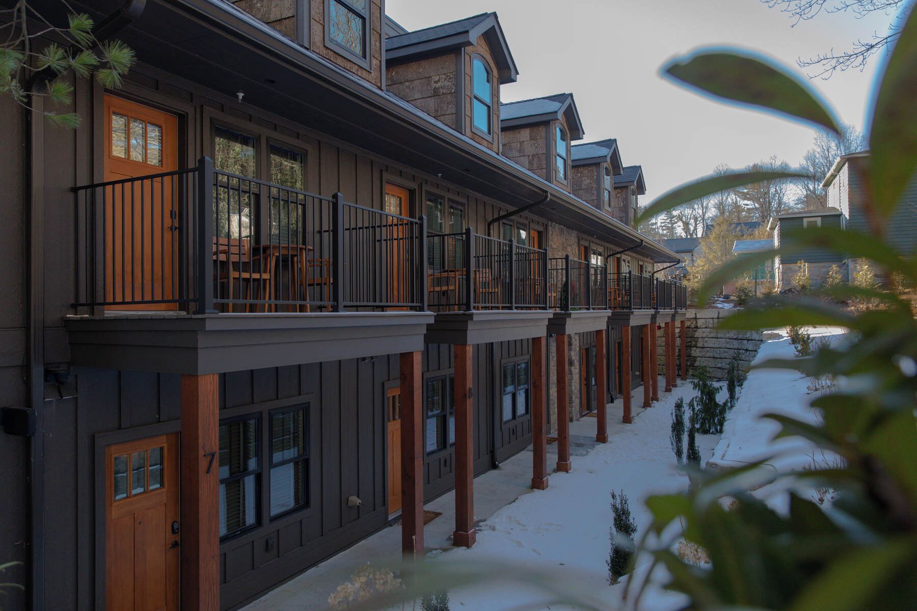 A multi-story building with a balcony on each floor, wooden doors, and a stone facade.