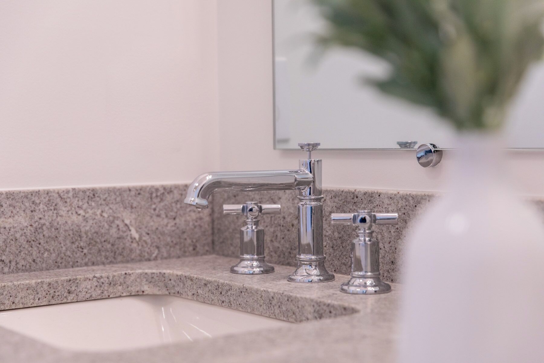 Un baño con encimera de granito, un lavamanos y un espejo arriba.
