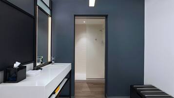 A modern bathroom with a white vanity, a black towel rack, and a glass shower door.