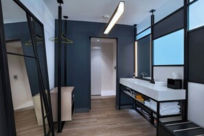 A modern bathroom with a large mirror, white countertop, and wooden flooring. - Aloft by Marriott Austin Southwest (Austin)