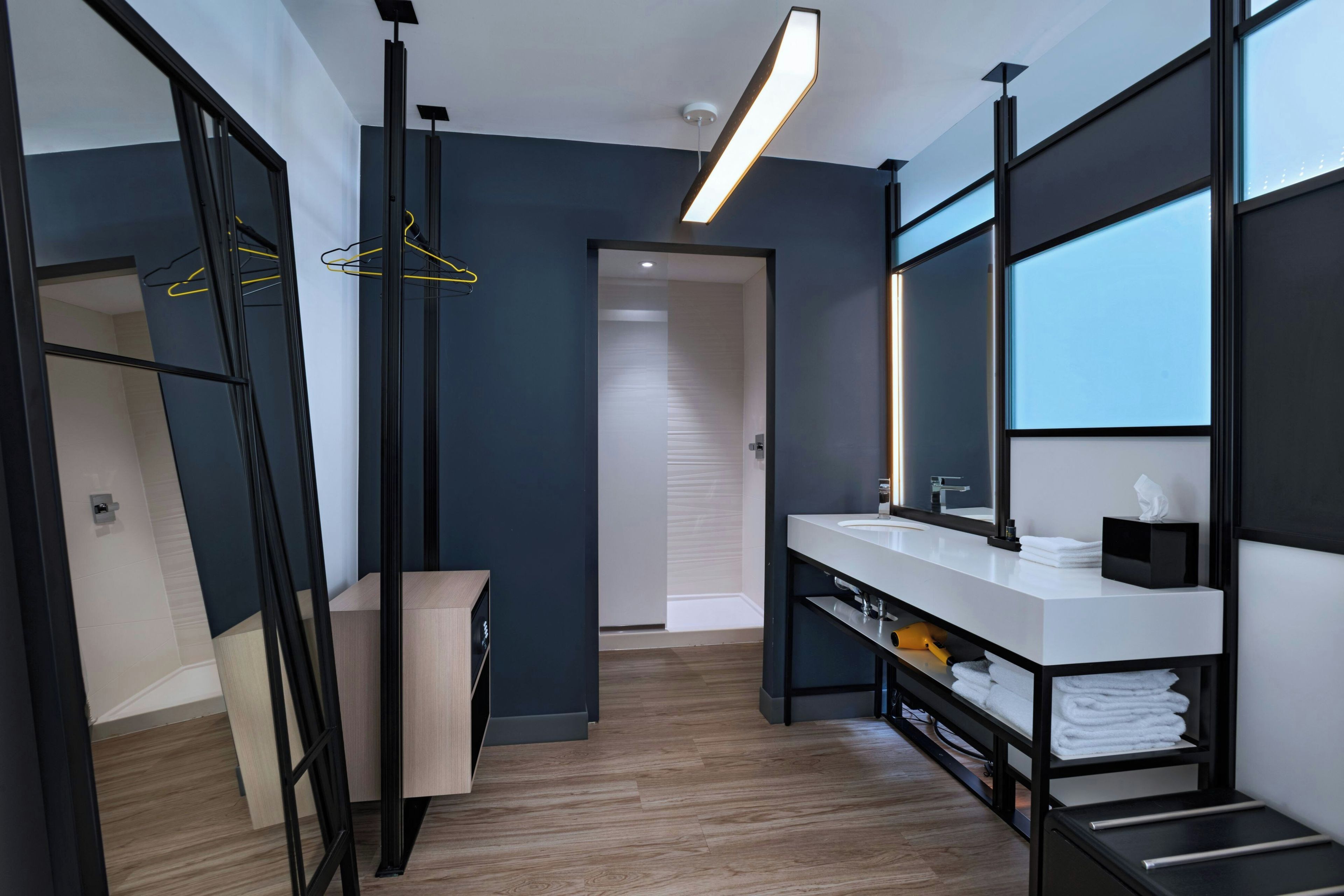 A modern bathroom with a large mirror, a white sink, and a towel rack.