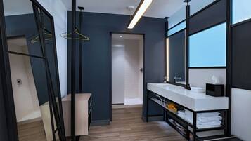 A modern bathroom with a large mirror, a white sink, and a towel rack.