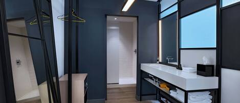 A modern bathroom with a large mirror, a white sink, and a towel rack.