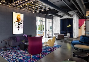A modern lounge area with a sofa, chairs, a coffee table, and a large abstract painting.