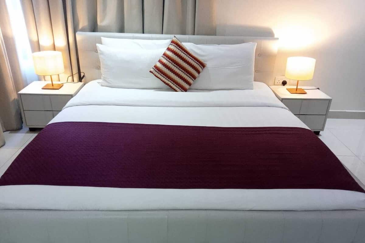 A hotel room with a large bed, two bedside tables, and a headboard.