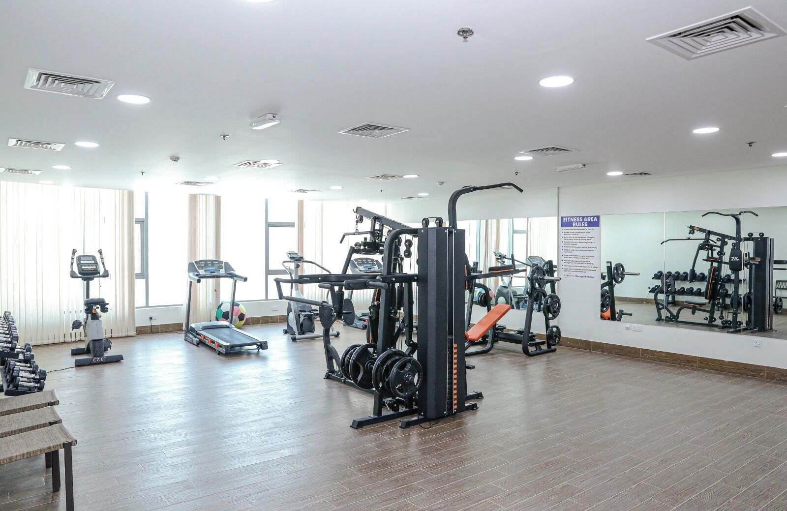A spacious fitness area with cardio machines, weightlifting equipment, and a mirrored wall.