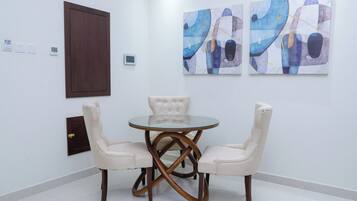 A dining area with a round glass table and two upholstered chairs.