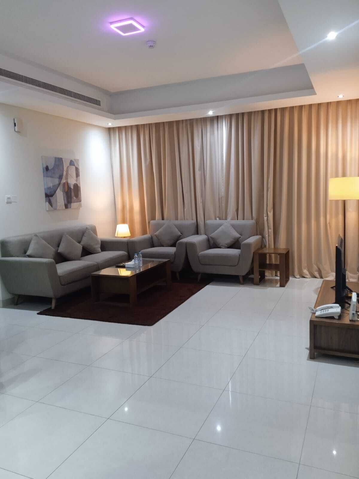 A modern living room with a sofa set, a coffee table, a lamp, and a television on a wooden side table.