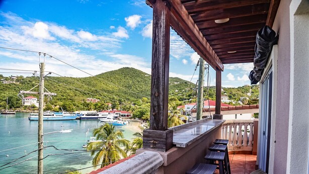 Un balcon avec vue sur un port de plaisance et sur une colline.