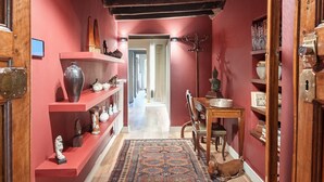 Un pasillo con paredes rojas, vigas de madera y estantes con adornos.
