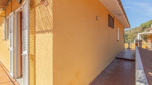 Ein Korridor mit gelber Wand, Holzboden und einer Tür mit weißen Fensterläden.