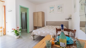 Ein Schlafzimmer mit einem Bett, einem Holzschrank, einer grünen Tür und einem Badezimmer mit einem Spiegel.