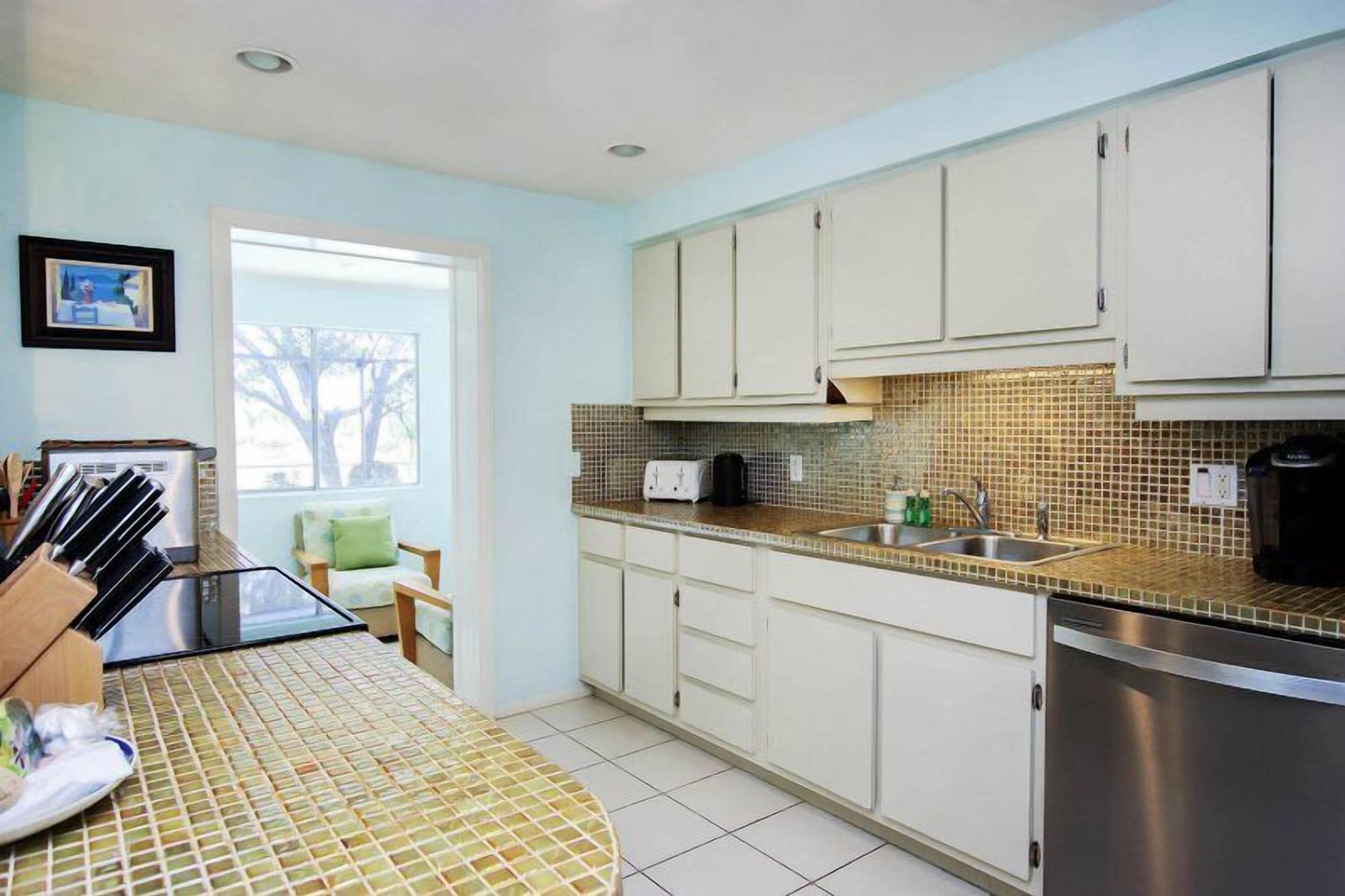 A kitchen with white cabinets, a tiled backsplash, and a stainless steel sink.