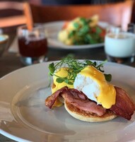 Prato de café da manhã com ovos Benedict, bacon e vegetais.