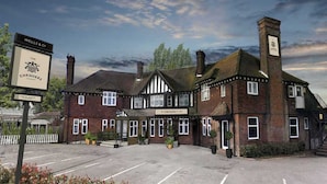 A traditional building with a sign for 'The Chequers' pub, featuring a classic architectural style with brickwork and white timber framing. - The Chequers (Knebworth)